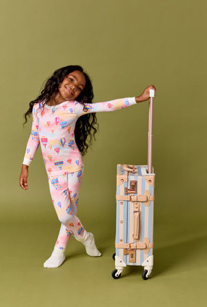 A Girl Wearing Serene Sunrise Long Sleeve Stretch Jersey Kids Pj Set with a bag