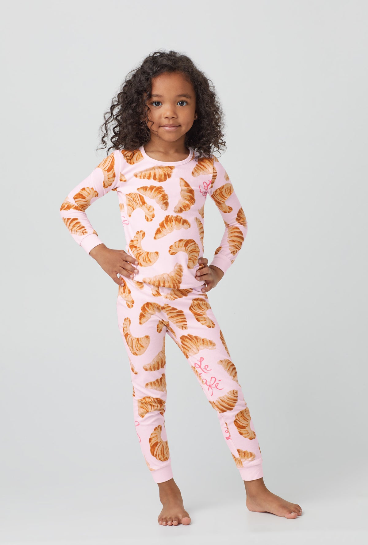 A girl wearing orange  Long Sleeve Stretch Jersey Kids PJ Set  with Le Cafe  print.