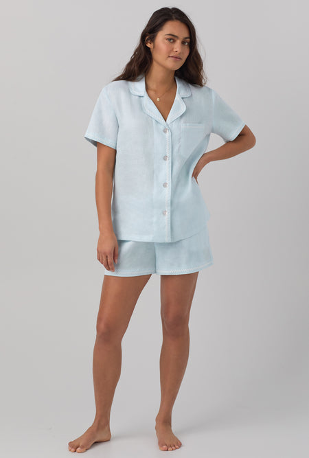 A lady wearing blue short sleeve classic shorty woven linen pj set with delicate blue print.