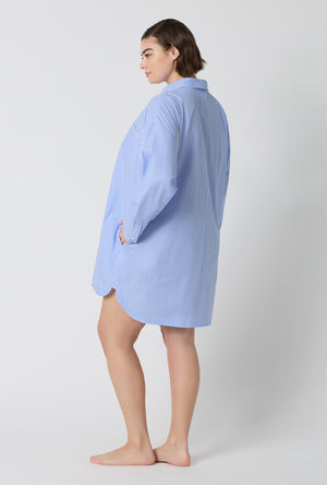 A Lady Wearing Plus Size French Stripe High Low Woven Supersoft Cotton Poplin Boyfriend Shirt in a side pose with one hand placed at the pocket
