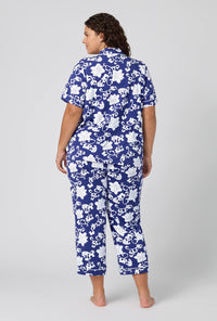 A Lady Wearing Plus Size Dynasty Blue Short Sleeve Classic Stretch Jersey Cropped Pj Set in a back view pose