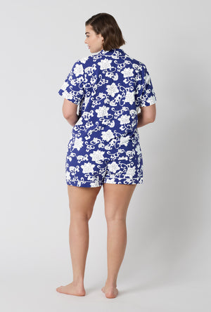 A Lady Wearing Plus Size Dynasty Blue Short Sleeve Classic Shorty Stretch Jersey Pj Set in a back view pose