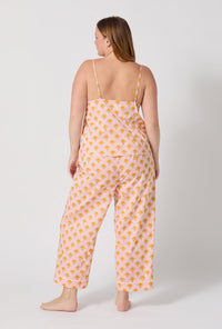 A Lady Wearing Plus Size Deco Sunset Cami Woven Cotton Poplin Cropped Pj Set facing back and looking to the side