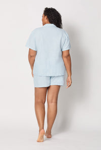 A lady wearing plus size Baby's Breath Blue Short Sleeve Classic Shorty Woven Linen Pj Set back view
