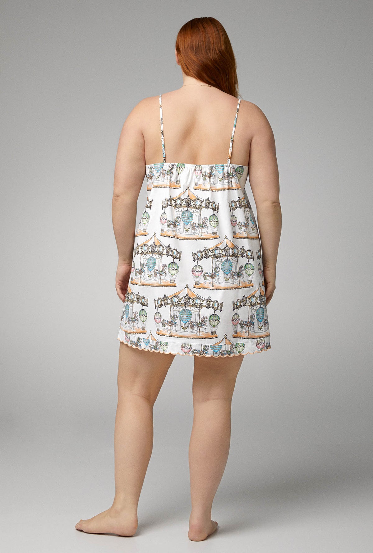 A lady wearing white  sleeveless woven cotton poplin plus size chemise with carousel scallop print.