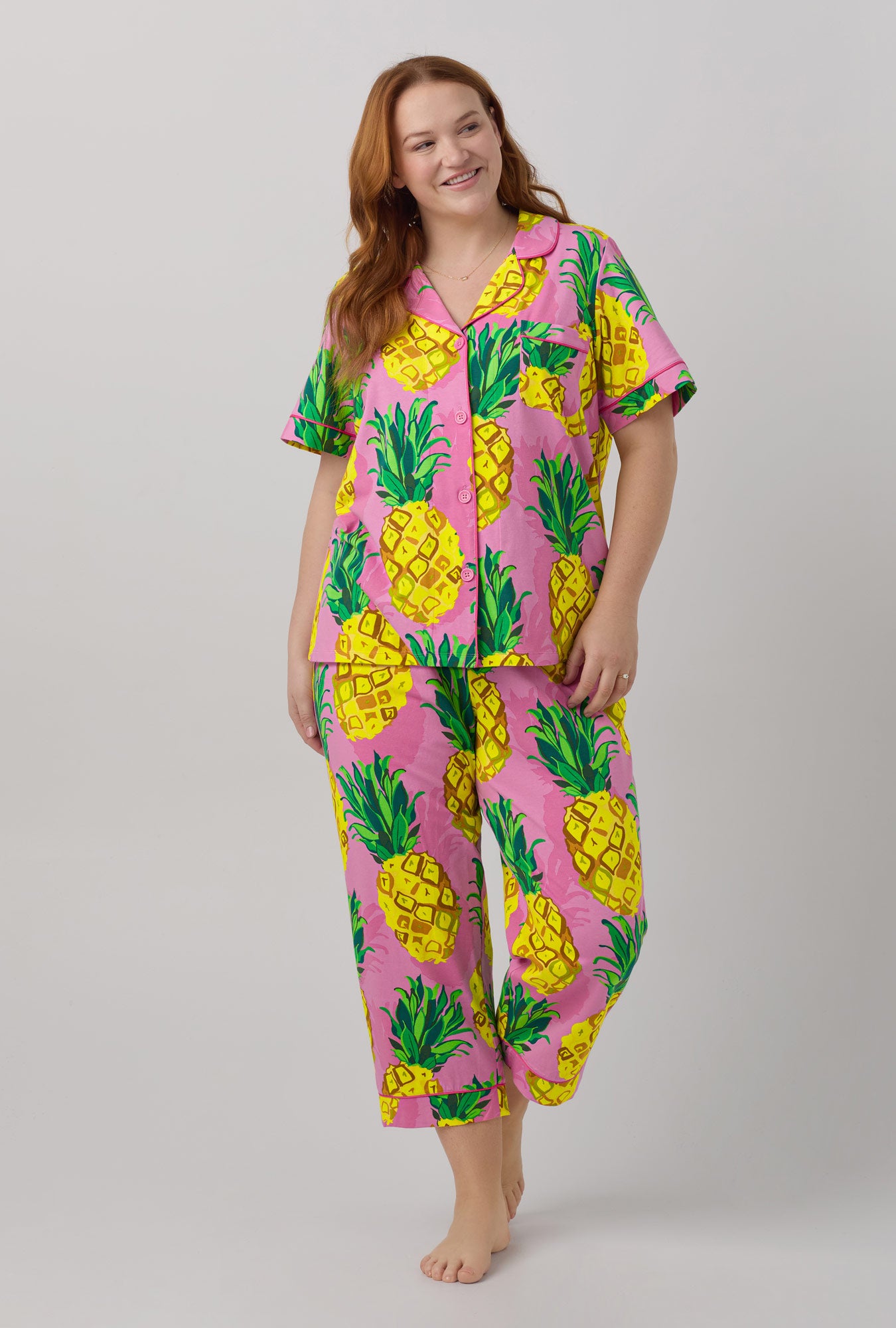 A lady wearing pink short sleeve classic stretch jersey cropped pj set with trina turk pineapples print.