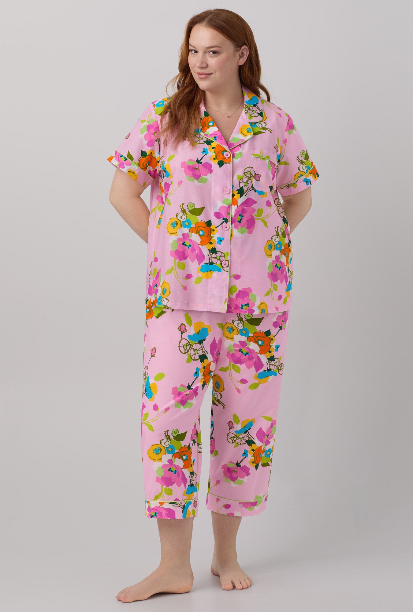 A lady wearing pink short sleeve classic woven cotton silk cropped plus size pj set with trina turk summer blooms print.