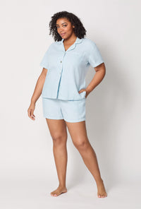 A lady wearing plus size Baby's Breath Blue Short Sleeve Classic Shorty Woven Linen Pj Set front view