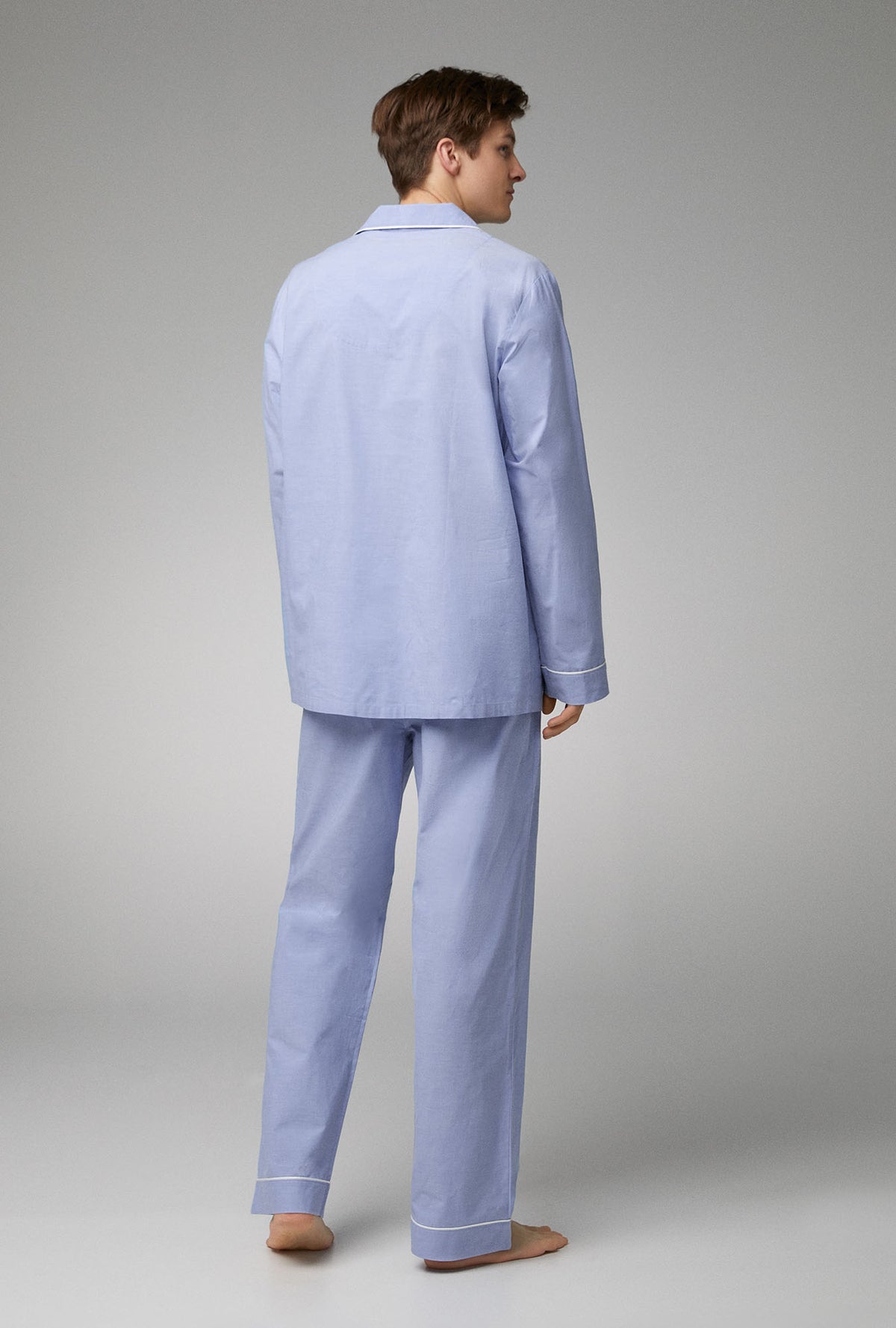 A man wearing blue long sleeve classic woven cotton poplin pj set with chambray print.