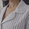 A lady wearing a long sleeve cotton sateen pj set with blue and white stripe pattern.