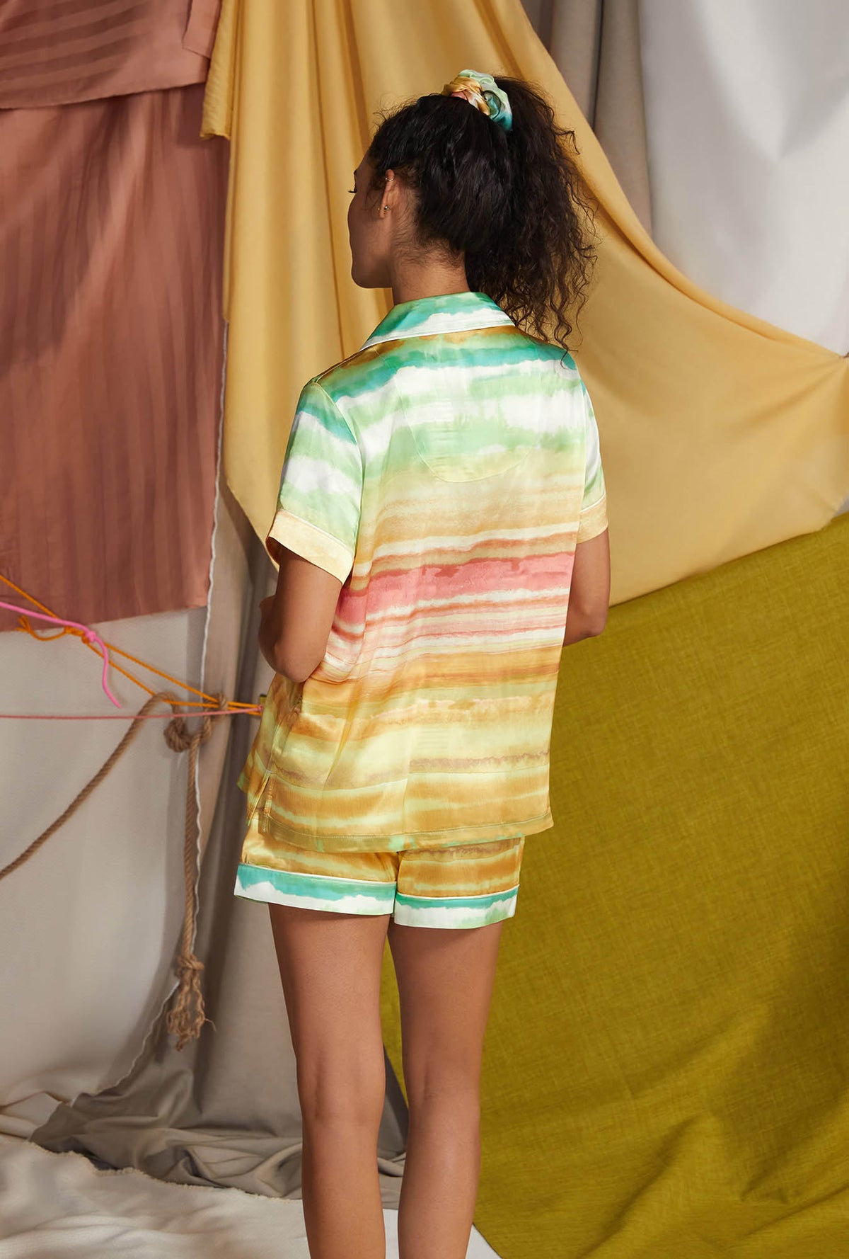 A lady wearing multi color short sleeve classic shorty woven silk pj set with island sunset print.