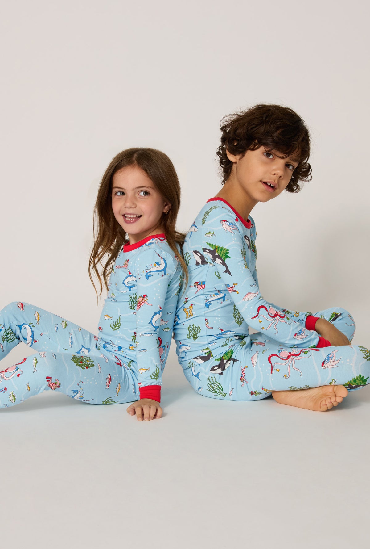 Girl and boy wearing Jingle All The Wave Long Sleeve Stretch Jersey Kids Pj Set sitting down