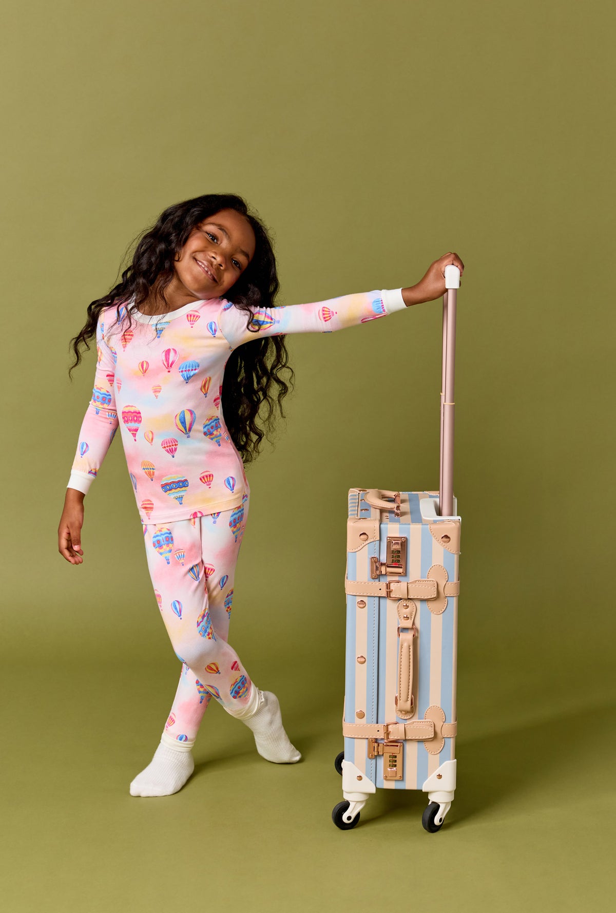 A Girl Wearing Serene Sunrise Long Sleeve Stretch Jersey Kids Pj Set with a bag