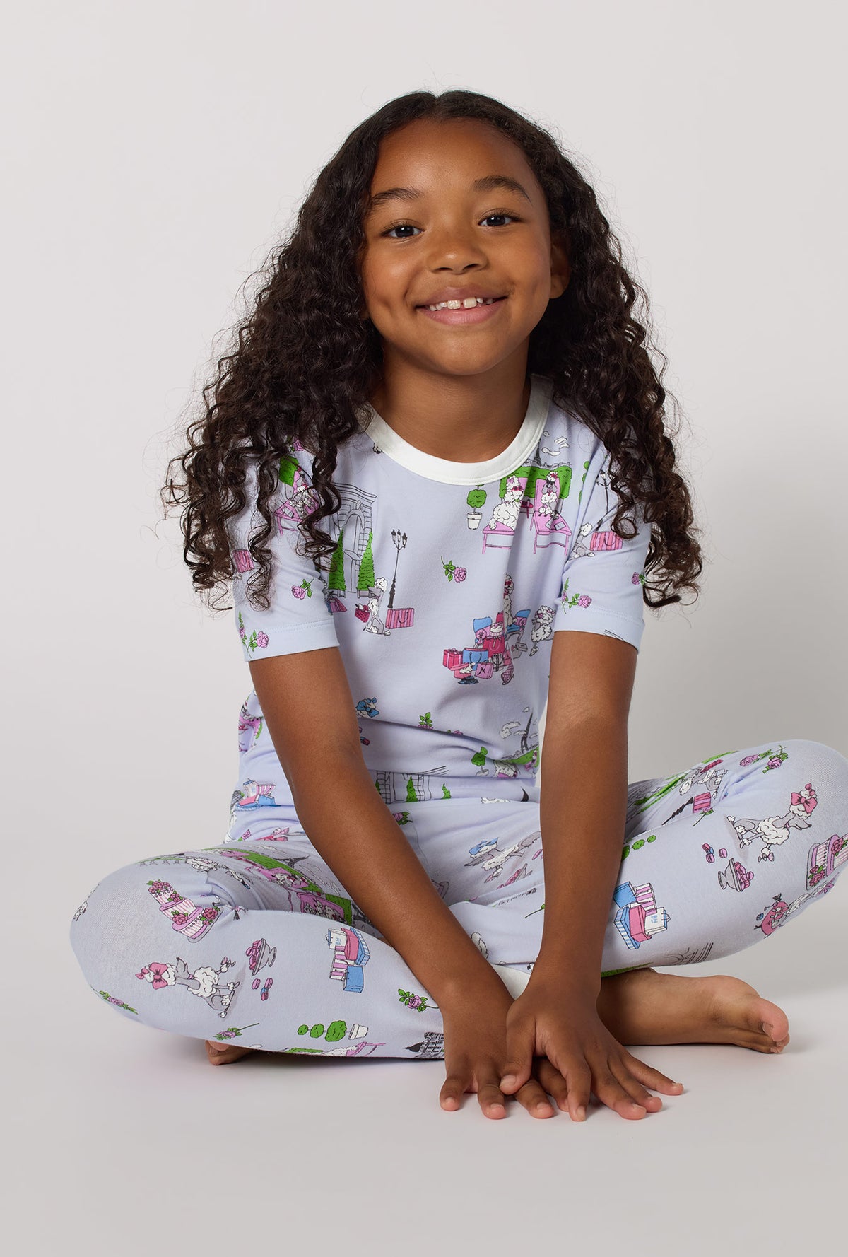 A Girl Wearing Belle Vie Short Sleeve Stretch Jersey Kids Pj Set in a sitting pose with a smile