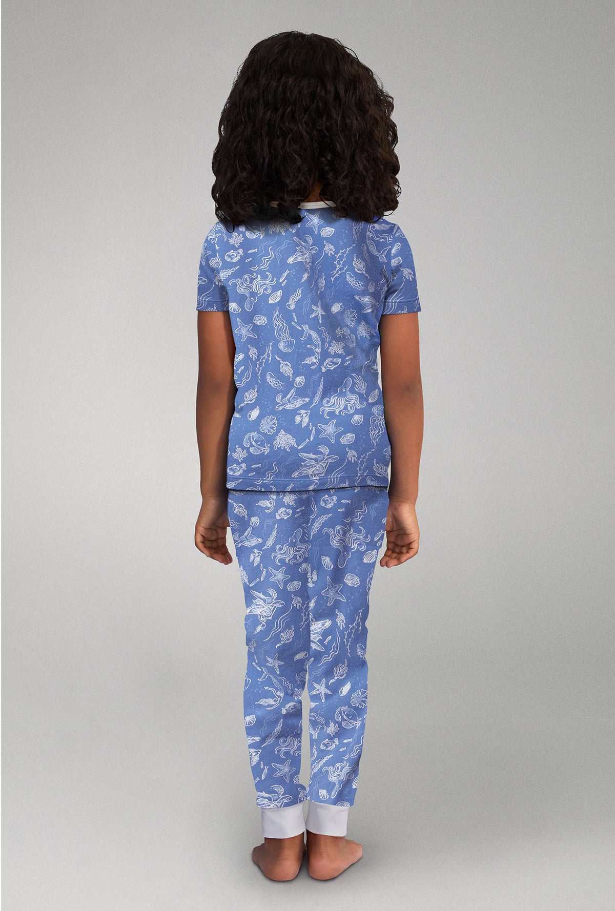A girl wearing blue short sleeve stretch jersey pj set with high tide print.