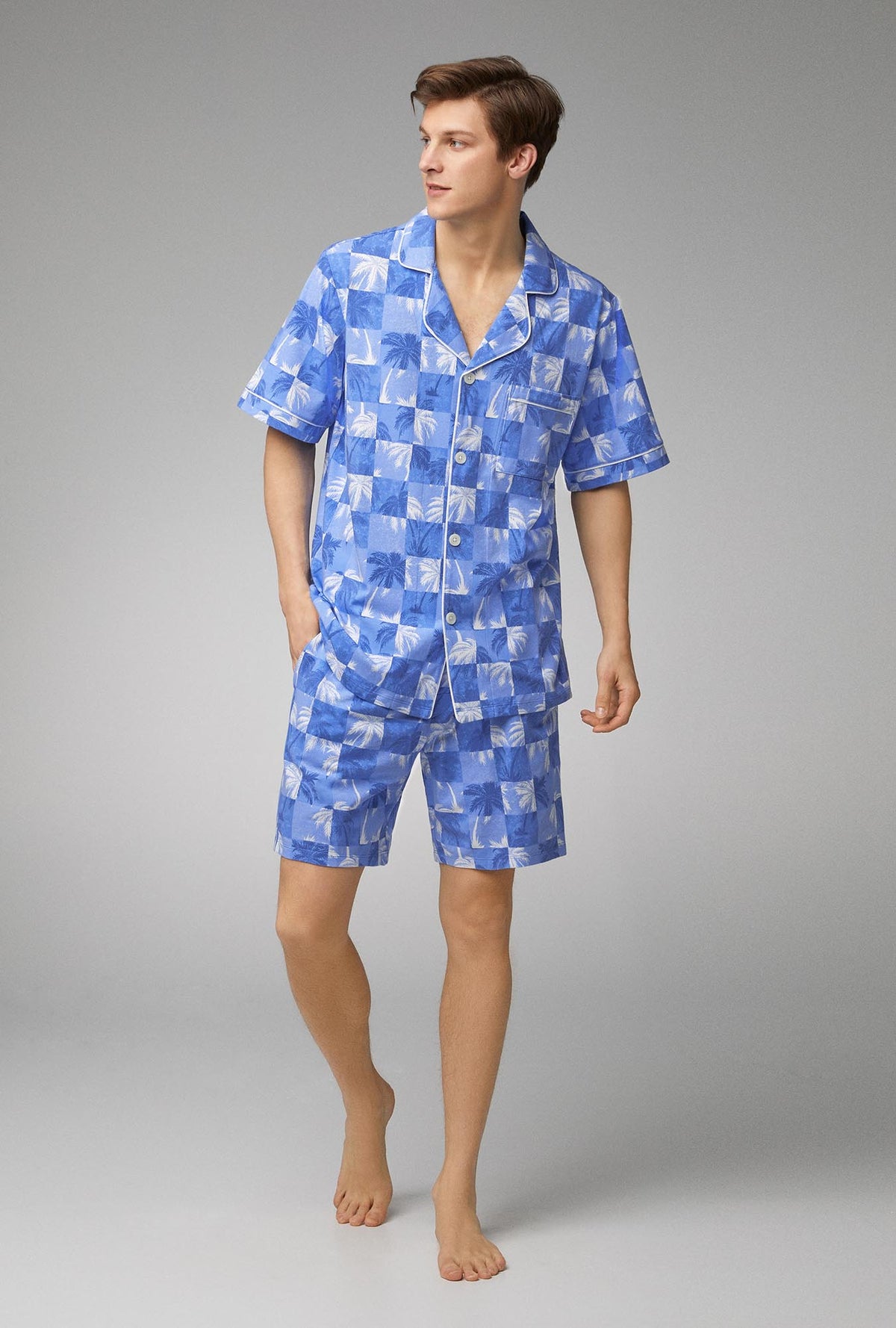 A man wearing blue short sleeve notch stretch jersey short pj set with cool palms print.