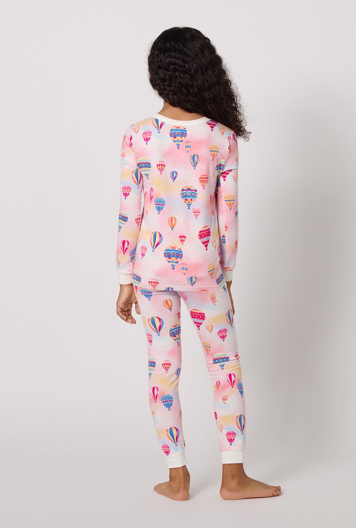 A Girl Wearing Serene Sunrise Long Sleeve Stretch Jersey Kids Pj Set in a back view pose