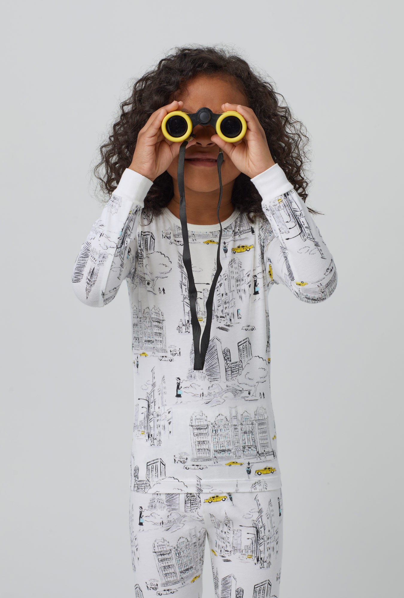 A kid wearing whiite long sleeve stretch jersey kids pj set with city that never sleeps print.