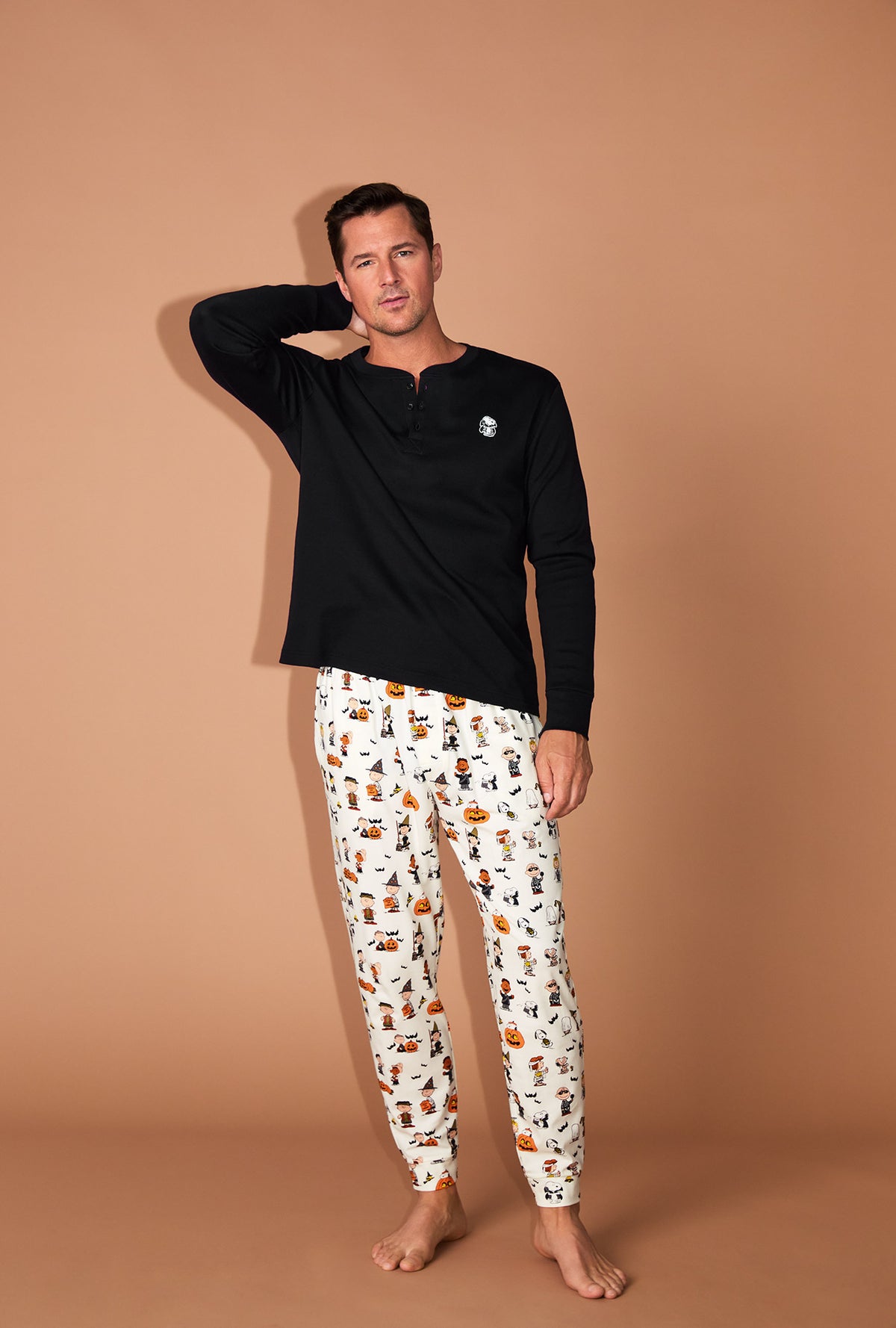A man wearing Peanuts® Snoopy&#39;s Halloween Men&#39;s Long Sleeve Henley and Jogger Stretch Jersey PJ Set