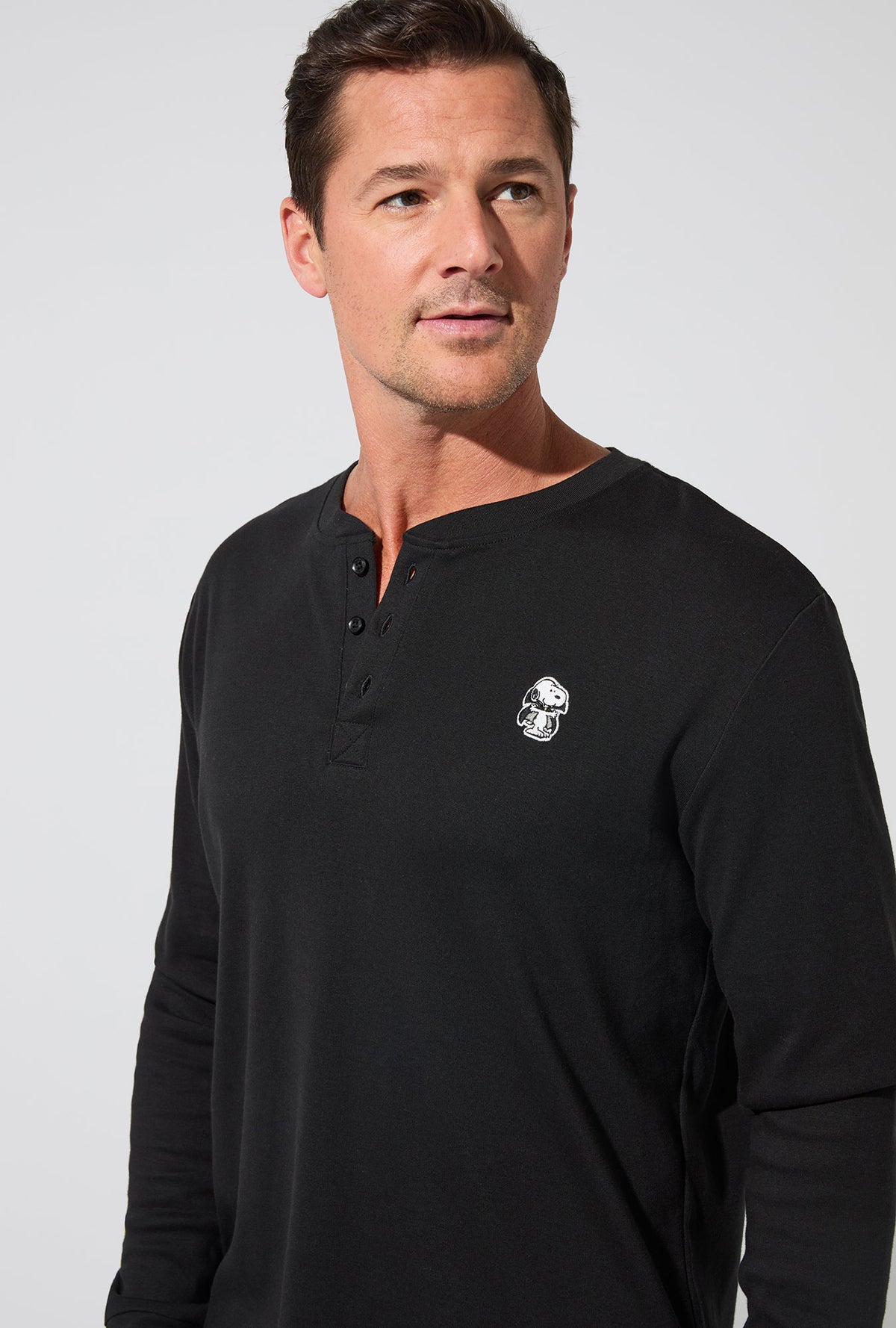 A man wearing Peanuts® Snoopy&#39;s Halloween Men&#39;s Long Sleeve Henley and Jogger Stretch Jersey PJ Set