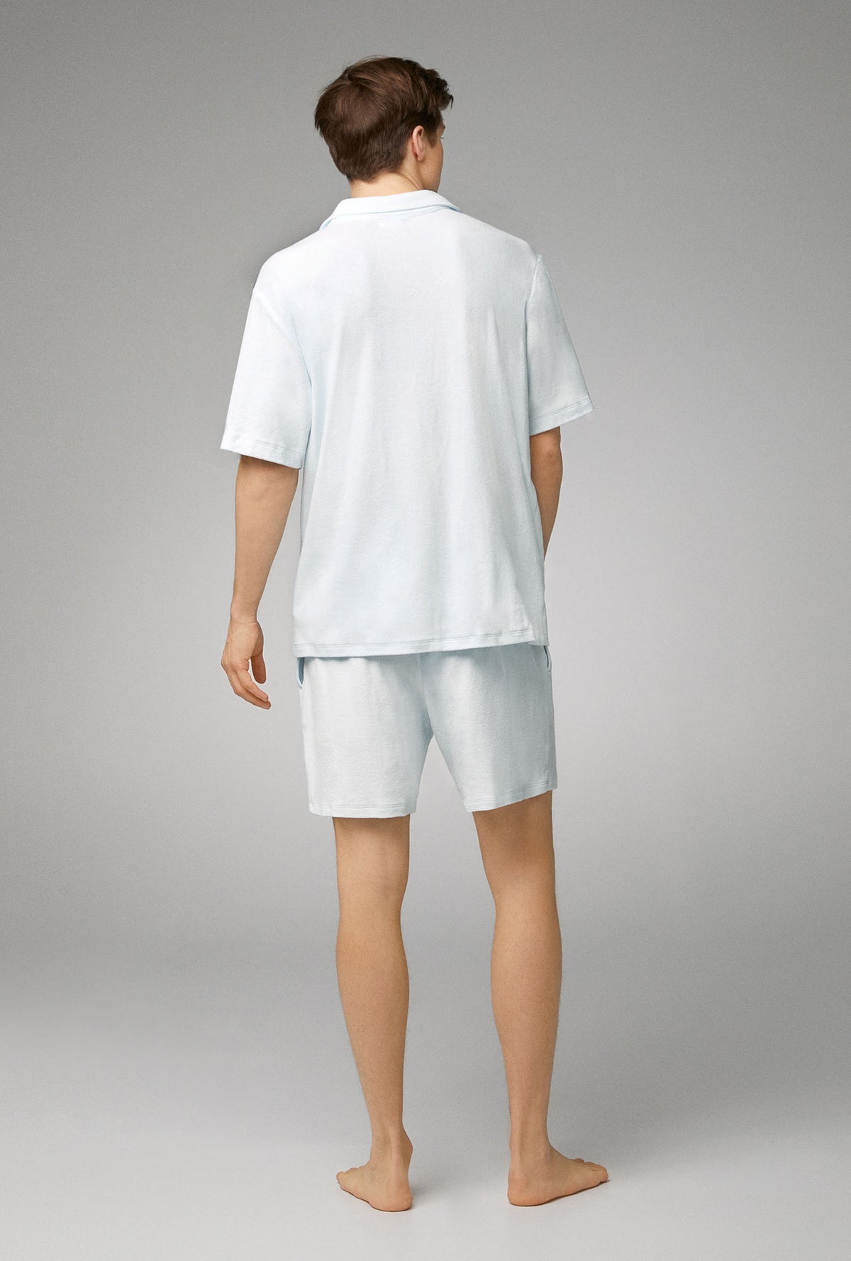 A man wearing white short sleeve notch woven cotton baby loop terry boxer pj set with country air print.