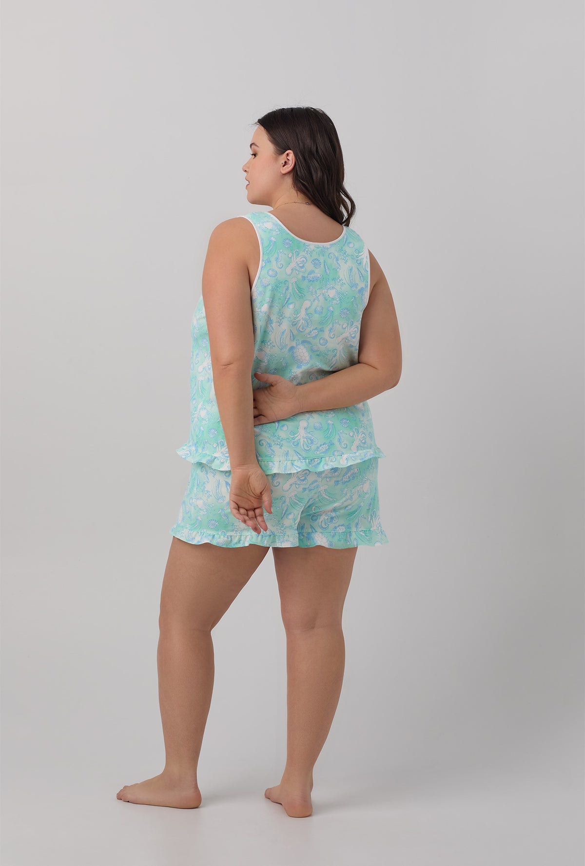A lady wearing white ruffle tank and shorty plus size pj set with aquatic life print