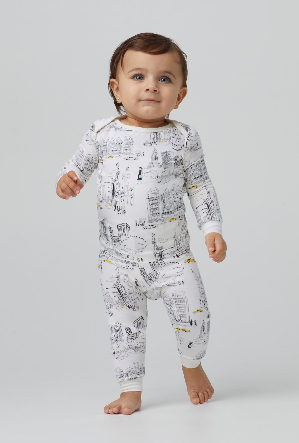 A baby wearing white long sleeve stretch jersey boo boo pj set with city that never sleeps print.