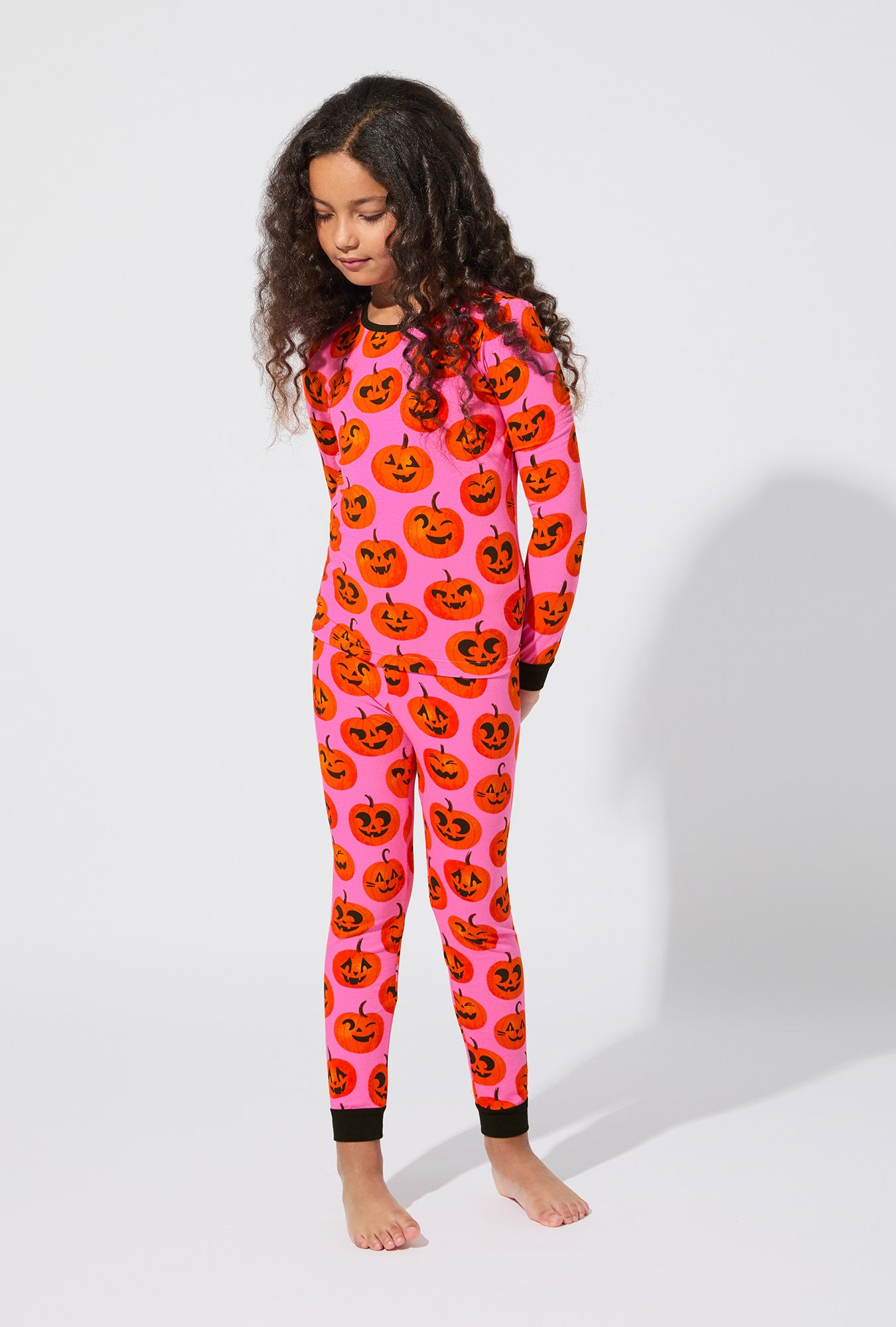 A girl wearing Jolly Jack-O-Lanterns Long Sleeve Stretch Jersey Kids PJ Set