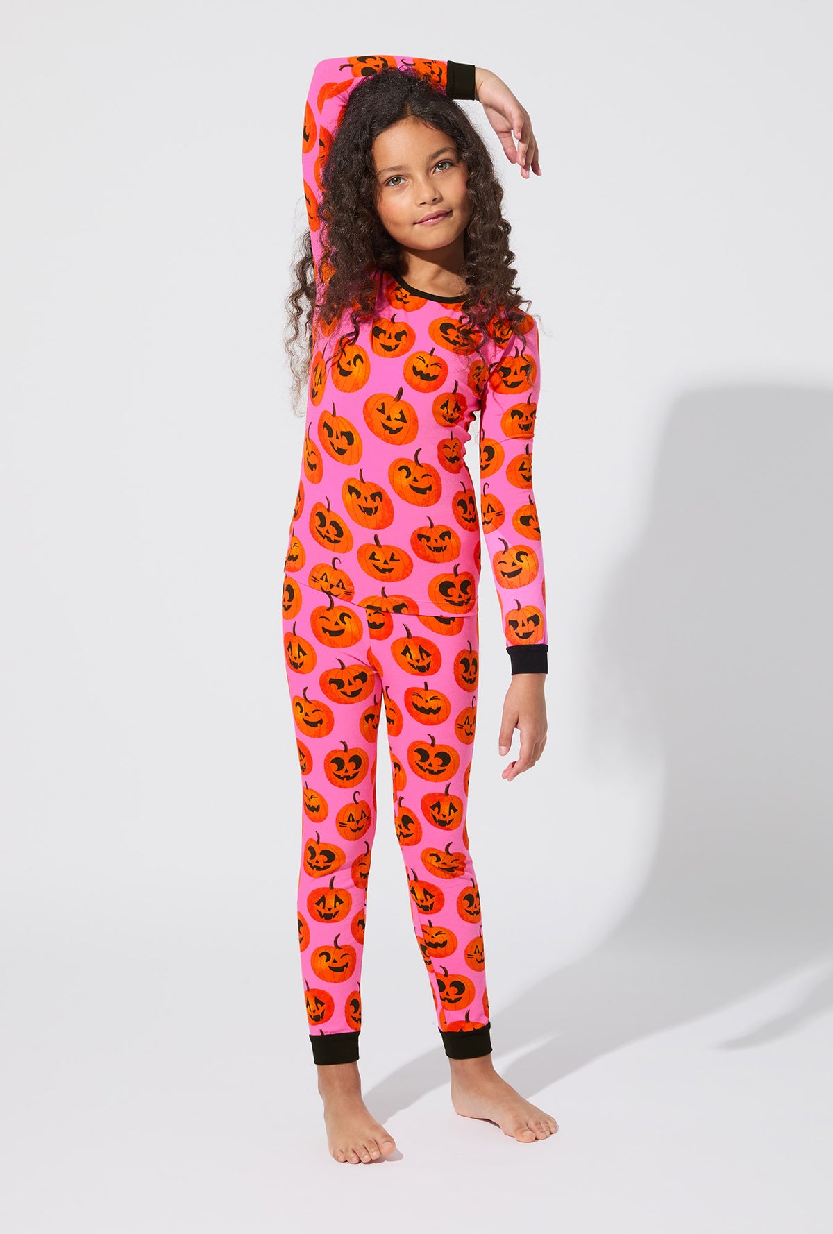 A girl wearing Jolly Jack-O-Lanterns Long Sleeve Stretch Jersey Kids PJ Set