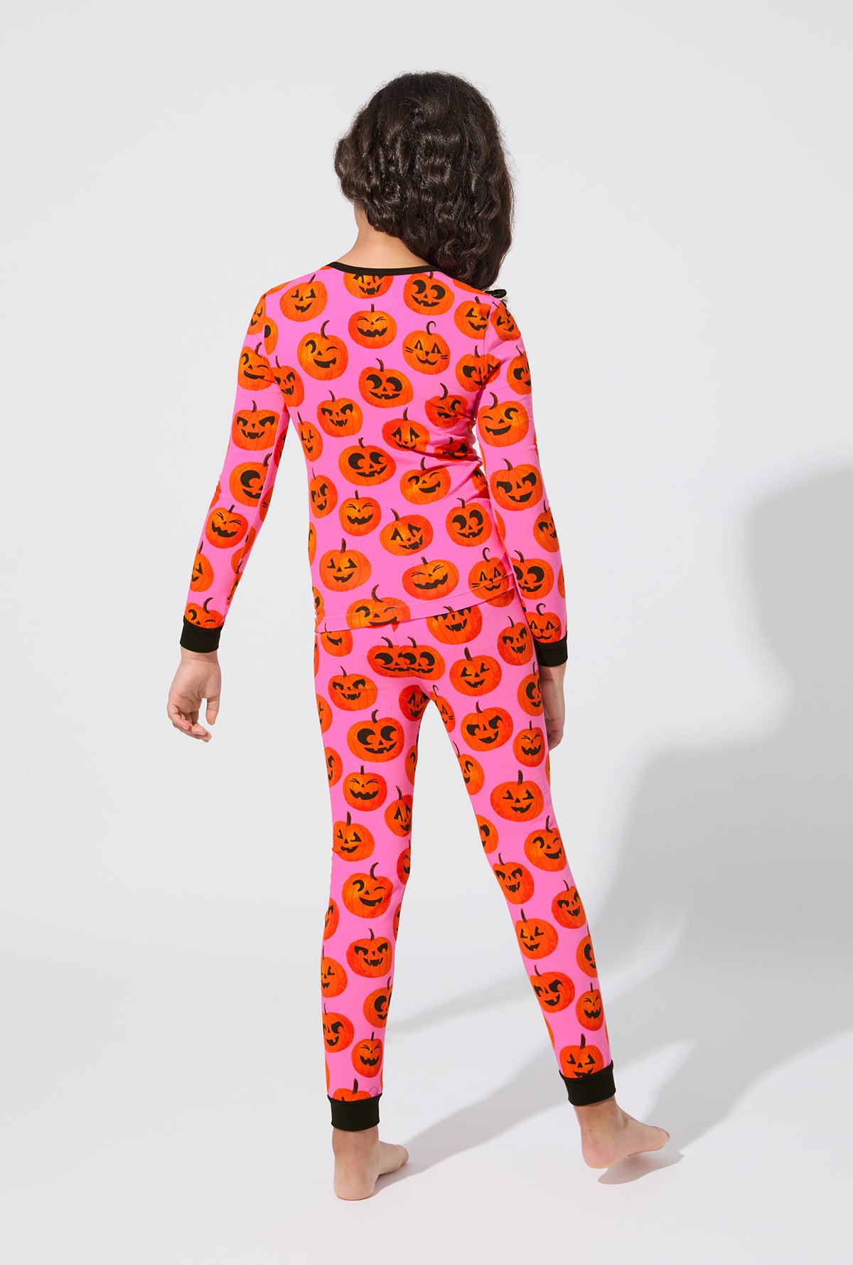 A girl wearing Jolly Jack-O-Lanterns Long Sleeve Stretch Jersey Kids PJ Set