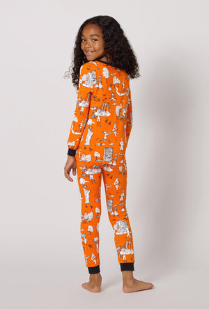 A Girl Wearing Orange Spooky In The City Long Sleeve Stretch Jersey Kids Pj Set in a back view pose