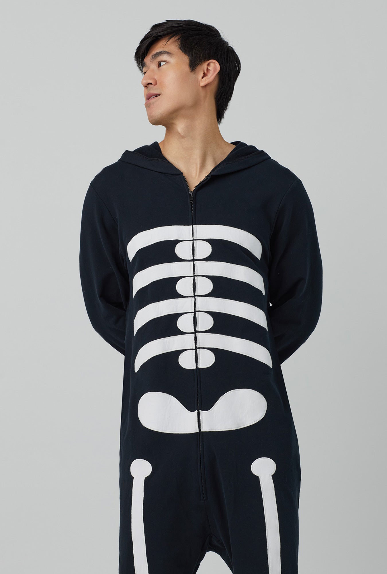 A man wearing unisex long sleeve french terry onesie with skeleton print