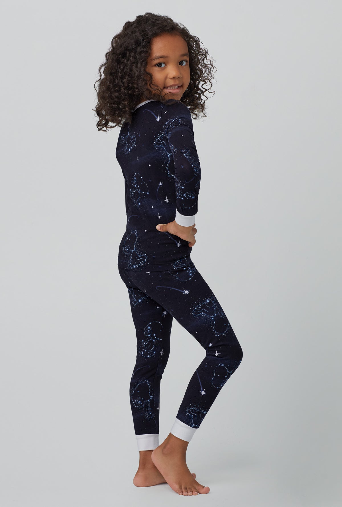 A girl wearing black long sleeve stretch jersey kids pj set with celestial snoopy print.