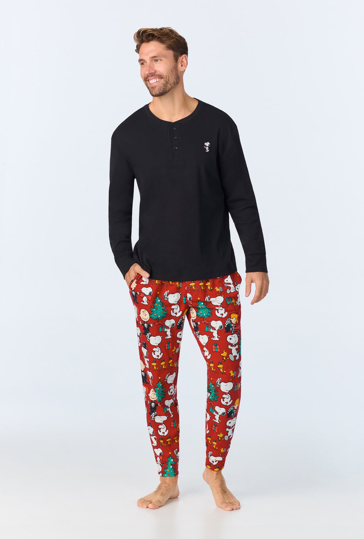 A man wearing Peanuts® Festive Fun Men&#39;s Long Sleeve Henley and Jogger Stretch Jersey PJ Set