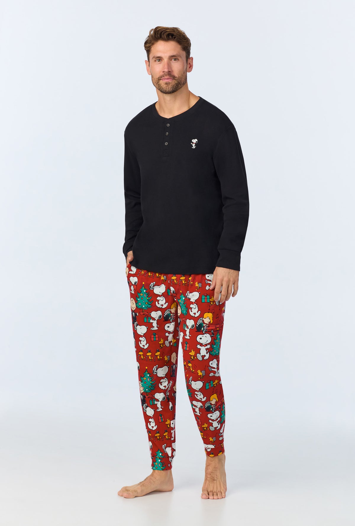 A man wearing Peanuts® Festive Fun Men&#39;s Long Sleeve Henley and Jogger Stretch Jersey PJ Set