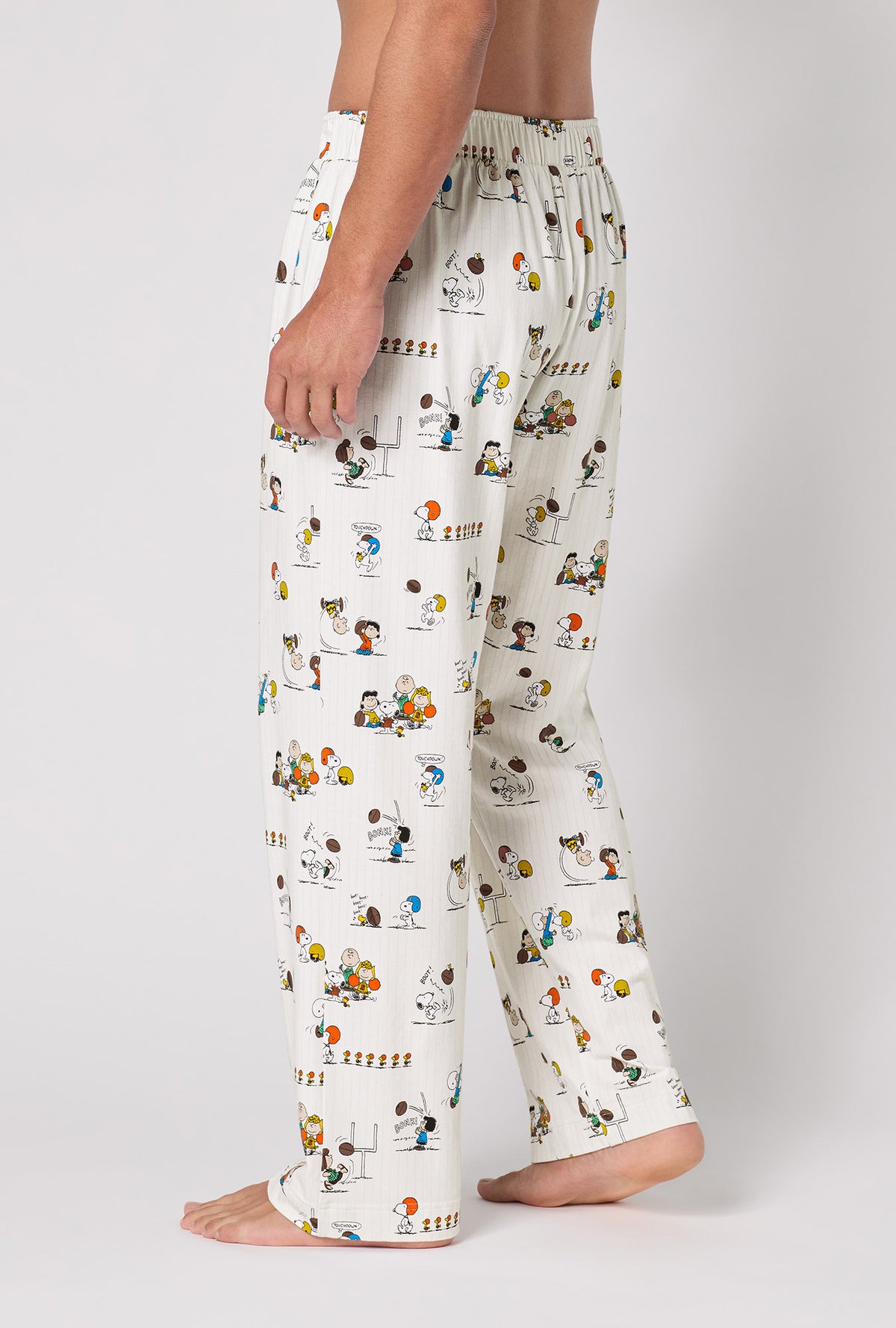 A Man Wearing Snoopy's Game Day Men's Stretch Jersey Pj Pant in a side view pose showing back look