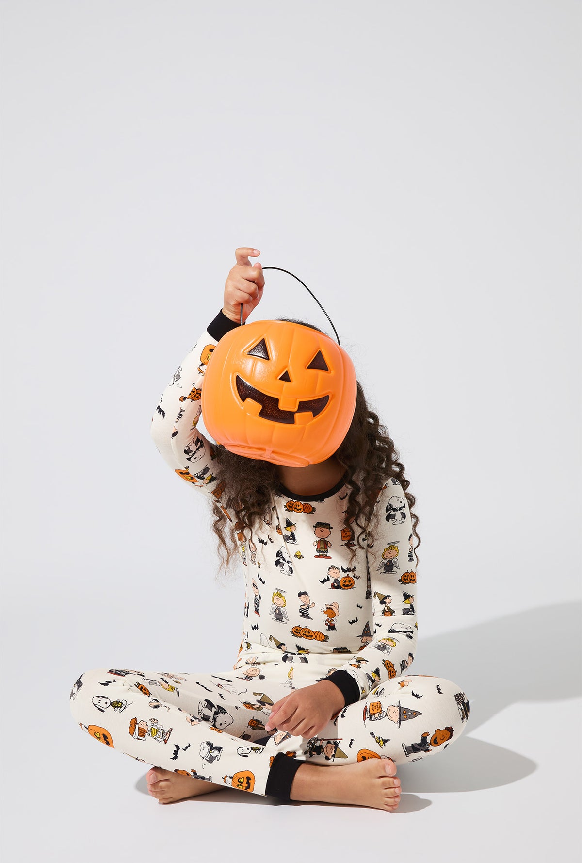 A girl wearing Peanuts® Snoopy&#39;s Halloween Long Sleeve Stretch Jersey Kids PJ Set
