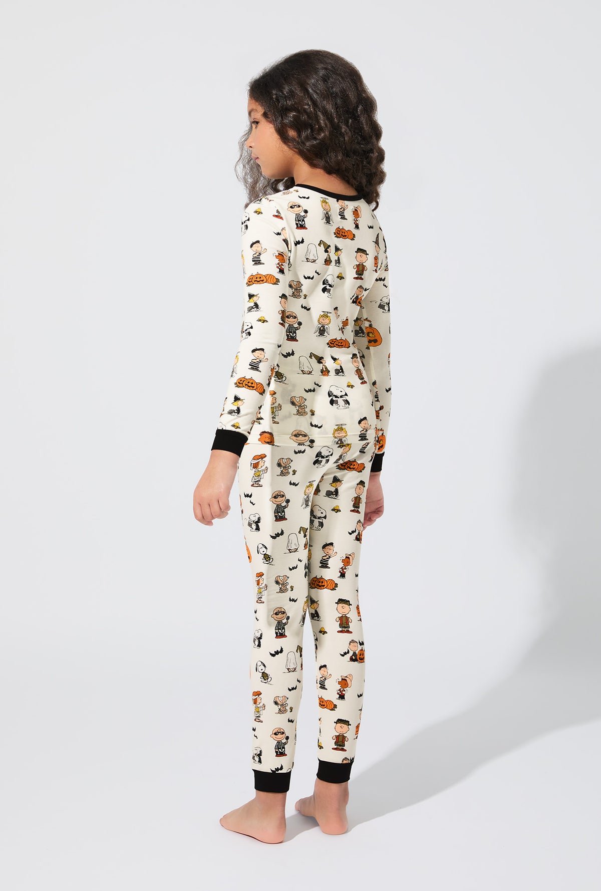 A girl wearing Peanuts® Snoopy&#39;s Halloween Long Sleeve Stretch Jersey Kids PJ Set