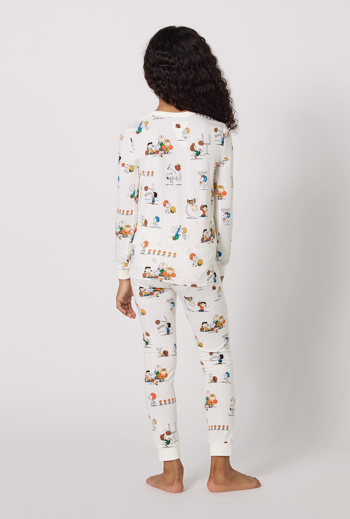A Girl Wearing Snoopy's Game Day Long Sleeve Stretch Jersey Kids Pj Set in a back view pose