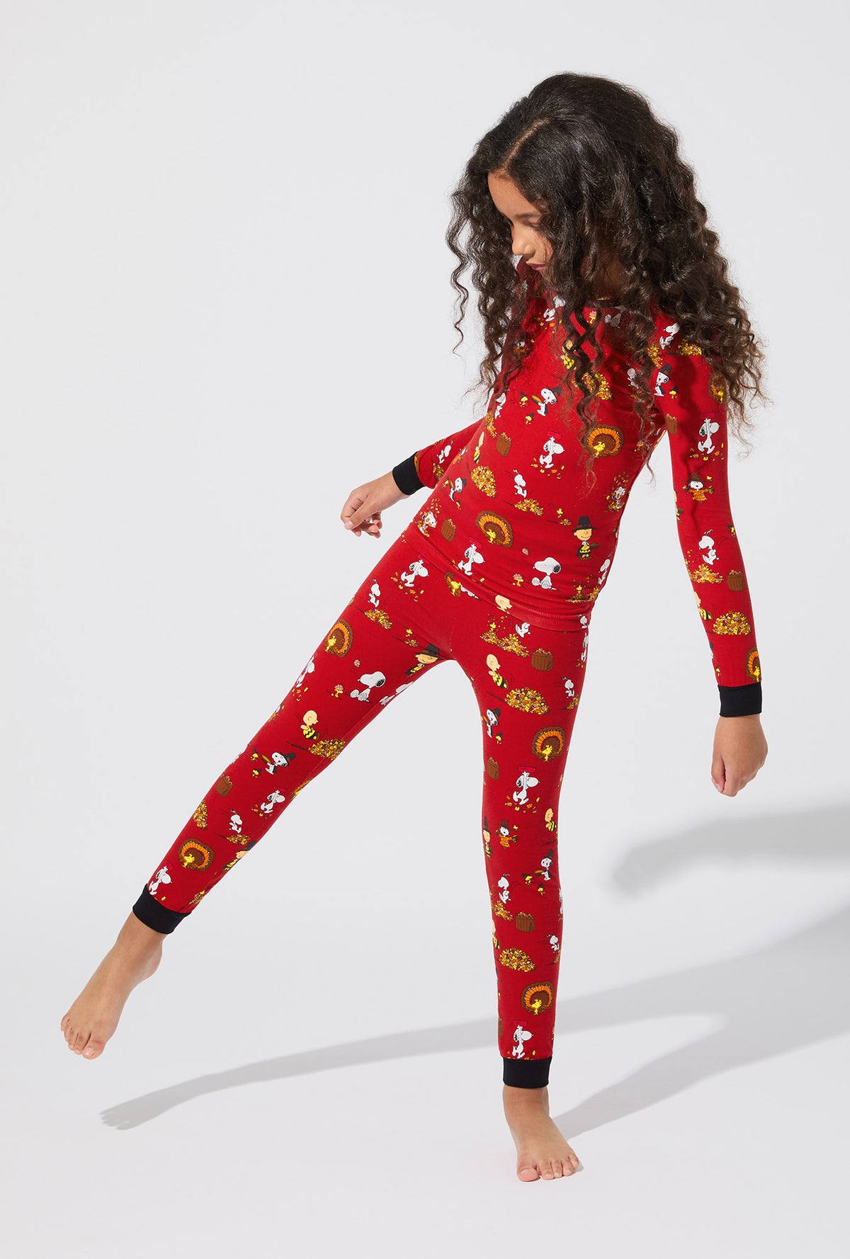 A girl wearing Peanuts® Snoopy&#39;s Thanksgiving Long Sleeve Stretch Jersey Kids PJ Set