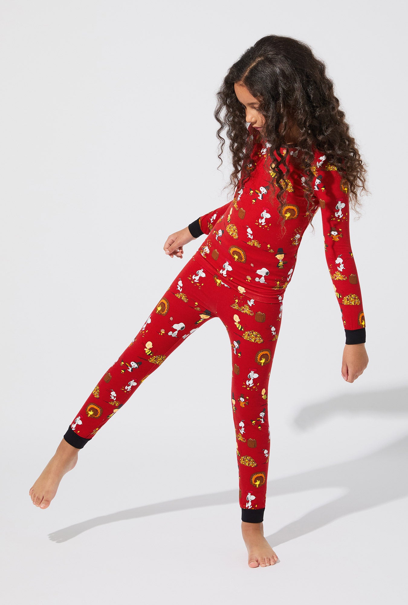 A girl wearing Peanuts® Snoopy's Thanksgiving Long Sleeve Stretch Jersey Kids PJ Set