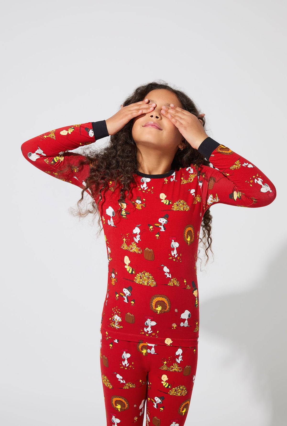 A girl wearing Peanuts® Snoopy&#39;s Thanksgiving Long Sleeve Stretch Jersey Kids PJ Set