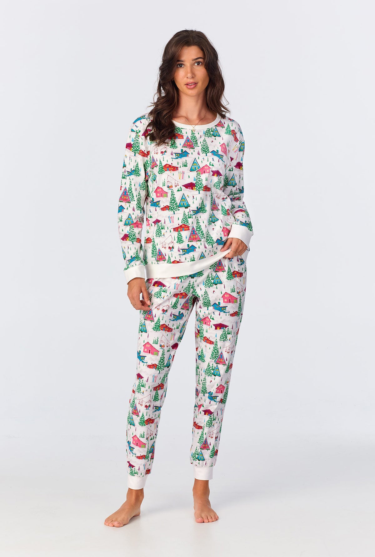 A lady wearing white long sleeve pullover  crew jogger stretch jersey pj set with alpine cabins print.