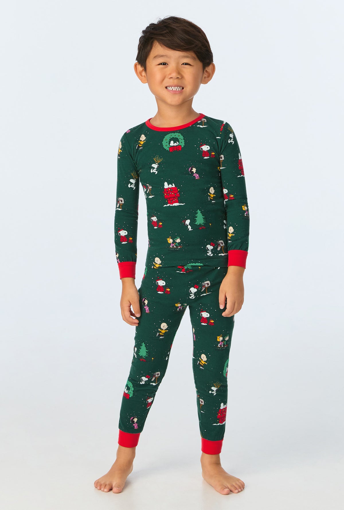 A child wearing Peanuts® Winter Holiday Long Sleeve Stretch Jersey Kids PJ Set