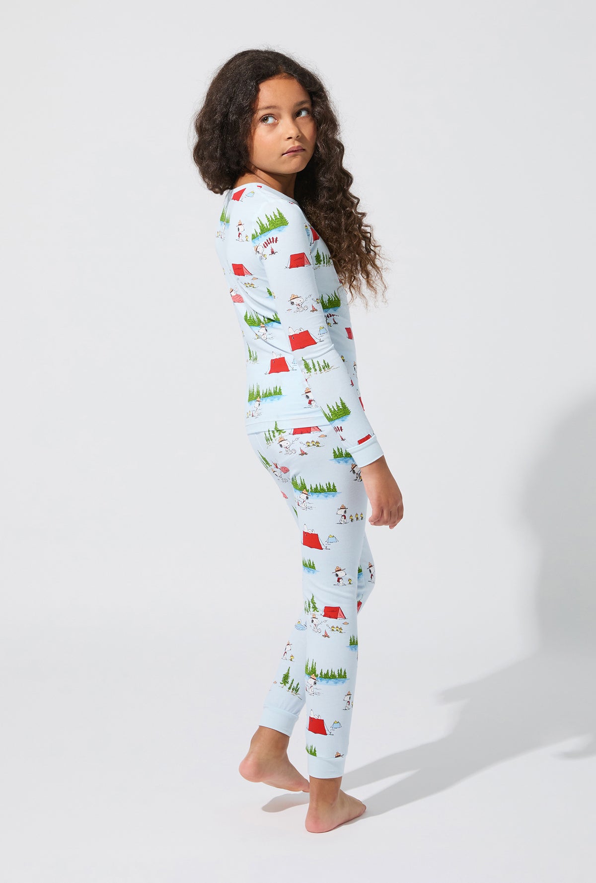 A girl wearing Peanuts® Camp Snoopy Long Sleeve Stretch Jersey Kids PJ Set
