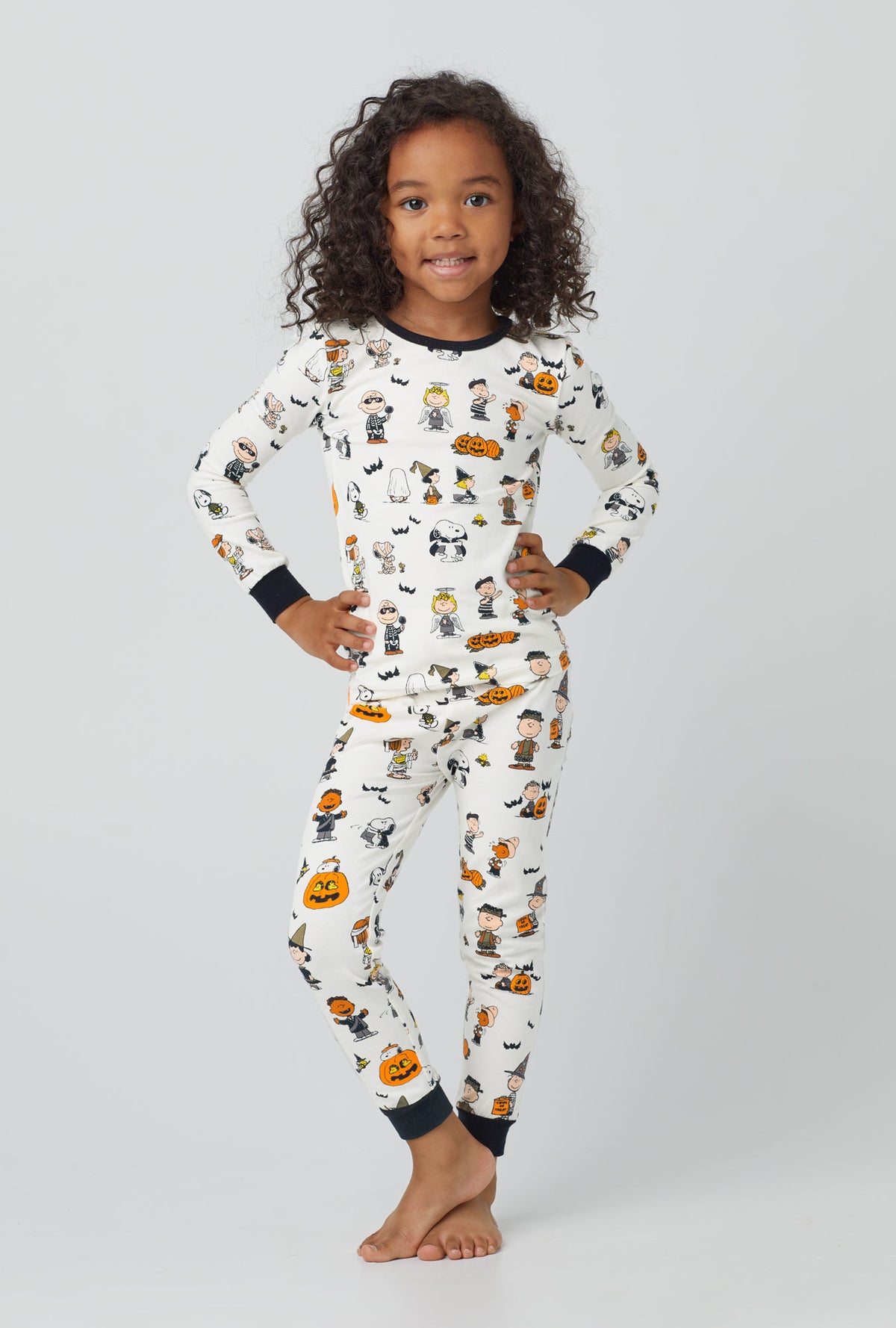 A girl wearing white long sleeve stretch jersey kids pj set with snoopys halloween print.