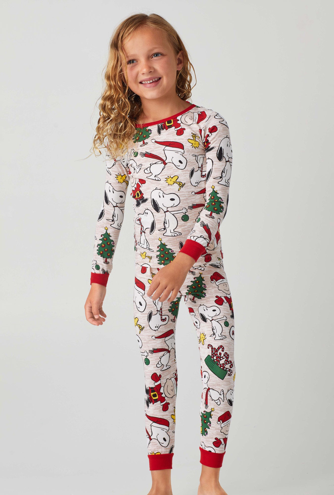 A kid wearing beige long sleeve classic stretch jersey pj set with merry christemas charlie brown print.