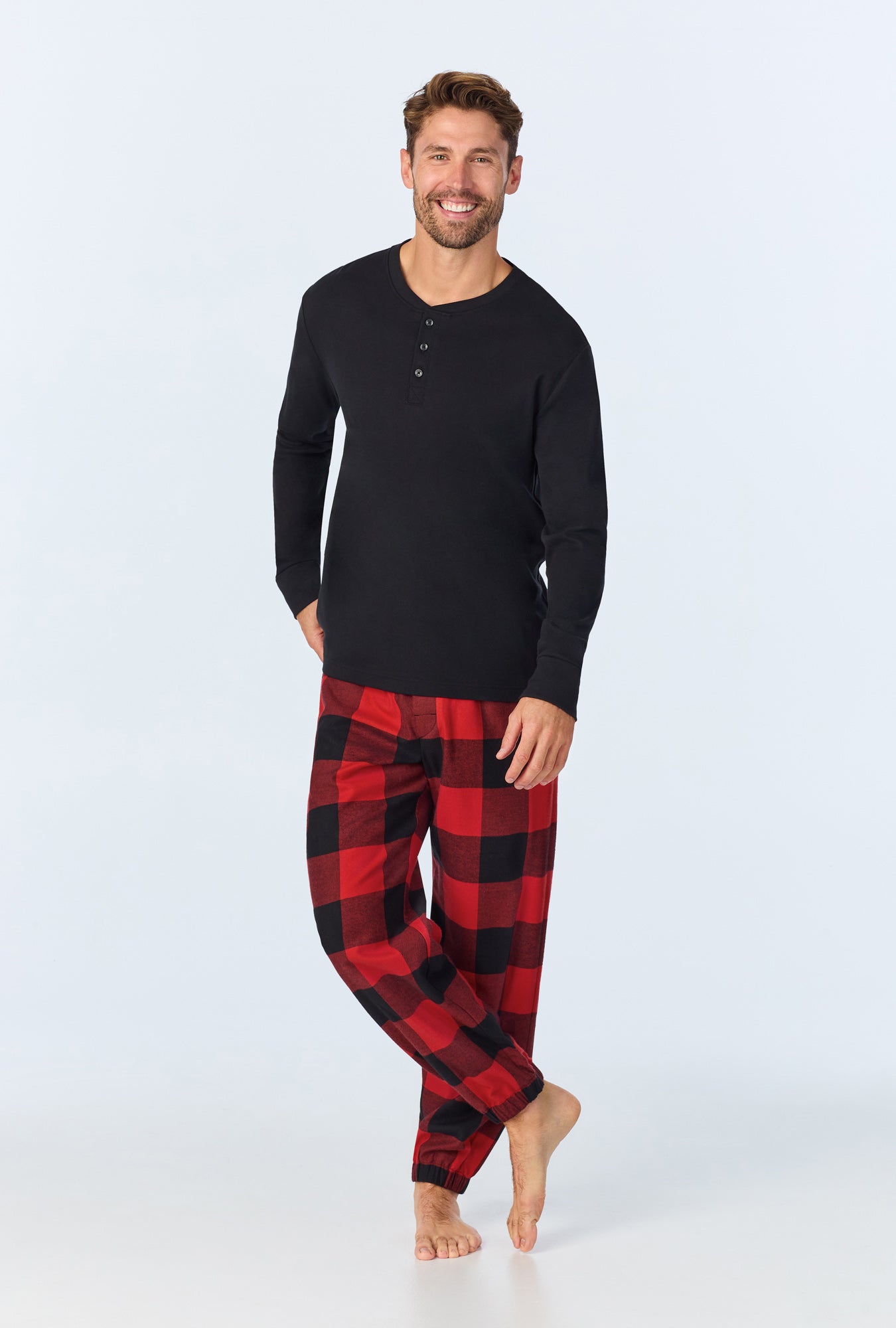 A man wearing Buffalo Check Men's  Long Sleeve Henley and Jogger Woven Portuguese Flannel PJ Set