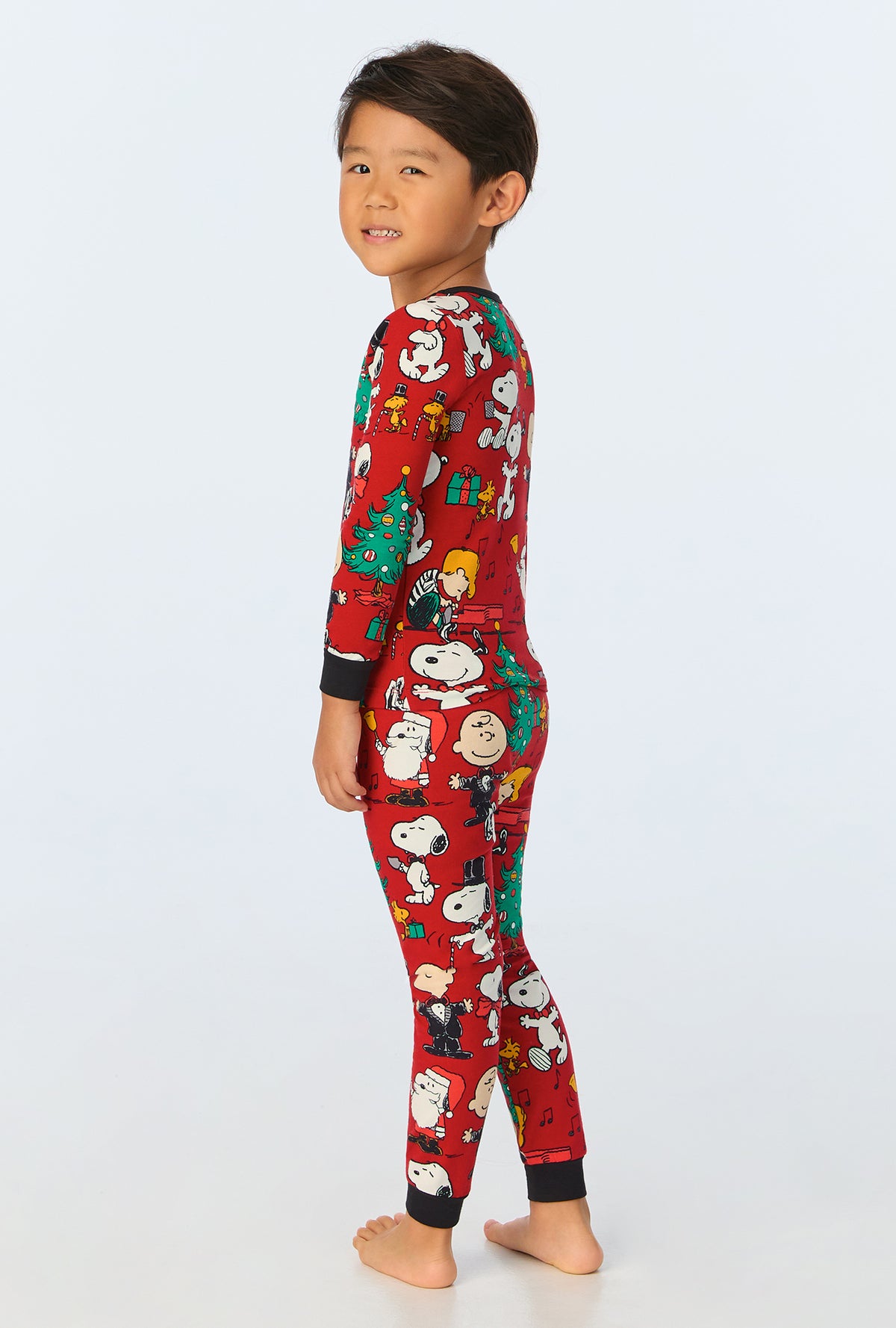 A child wearing Peanuts® Festive Fun Long Sleeve Stretch Jersey Kids PJ Set