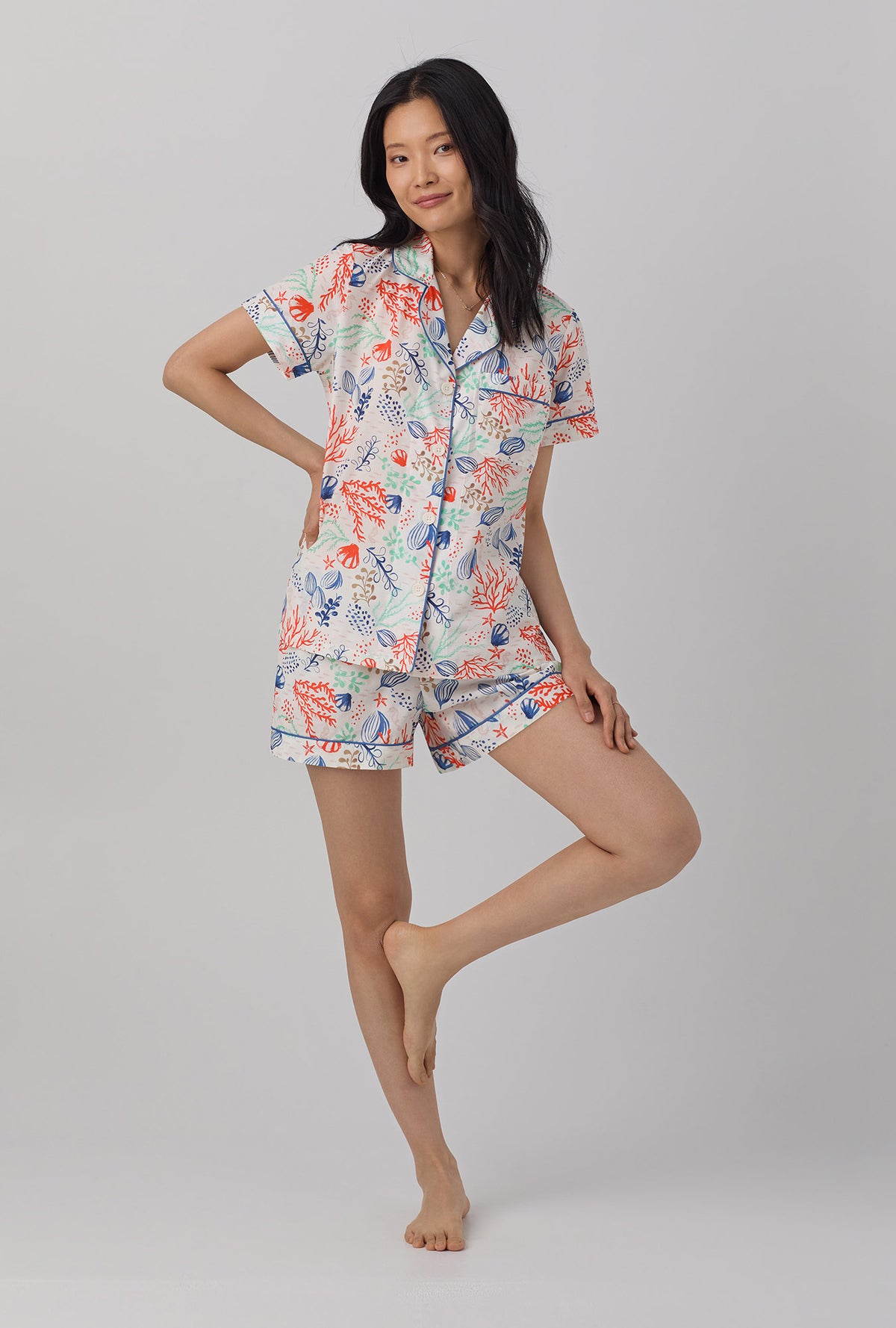 A lady wearing short sleeve classic pj set with coral reef print.